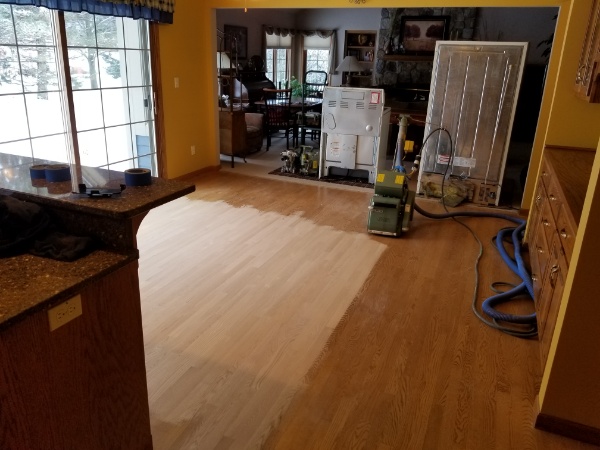 Our flooring contractors strip the original finish to begin this kitchen hardwood restoration